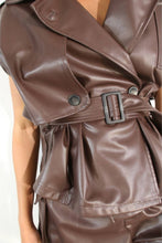 Load image into Gallery viewer, Close-up of a model wearing the Chocolate Luxe faux leather set, highlighting the structured sleeveless jacket, oversized lapels, adjustable buckle belt, and matching chocolate-brown shorts.