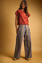Load image into Gallery viewer, Model wearing Retro Revival Striped Wide-Leg Jeans with multicolor vertical stripes, a high-rise waist, dramatic wide-leg silhouette, and raw-edge hems.