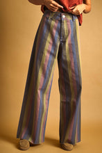 Load image into Gallery viewer, Model wearing Retro Revival Striped Wide-Leg Jeans with multicolor vertical stripes, a high-rise waist, dramatic wide-leg silhouette, and raw-edge hems.