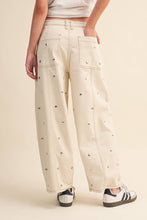 Load image into Gallery viewer, Model wearing cream barrel-leg jeans embellished with silver stud details throughout, featuring a high-rise waist and relaxed statement silhouette.