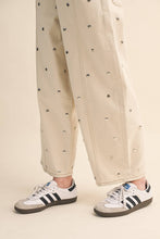 Load image into Gallery viewer, Model wearing cream barrel-leg jeans embellished with silver stud details throughout, featuring a high-rise waist and relaxed statement silhouette.