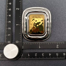 Load image into Gallery viewer, Pair of oversized two-tone statement earrings featuring sculptural rounded rectangular silver-tone frames and raised polished gold-tone centers.