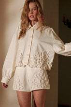 Load image into Gallery viewer, Model wearing écru tailored shorts with oversized floral appliqué embroidery paired with coordinating top in a soft neutral ivory/yellow tone.