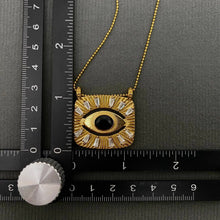 Load image into Gallery viewer, 18K gold-plated All Seeing Eye pendant necklace featuring a black center stone, clear zircon accents and textured sunburst design.