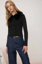 Load image into Gallery viewer, Woman wearing a black cardigan with fur collar and blue jeans on a white background