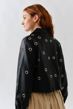 Load image into Gallery viewer, Woman wearing a Glam Expressway black leather jacket with eyelets on a plain background