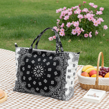 Load image into Gallery viewer, Black and white patterned tote bag on a picnic blanket with fruits and flowers in the background