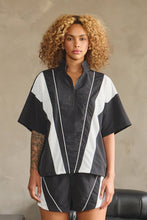 Load image into Gallery viewer, Black oversized half-zip nylon top with white mesh contrast panels, mock neckline, white piping, short sleeves, and adjustable drawcord hem.