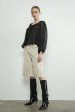 Load image into Gallery viewer, Woman wearing a black blouse, beige denim bermuda shorts, and black knee-high boots against a white background