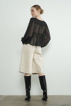 Load image into Gallery viewer, Woman wearing a black sheer top, beige bermuda shorts, and black boots against a white background