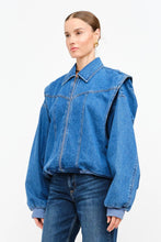 Load image into Gallery viewer, Model wearing an indigo denim bomber jacket with structured shoulders, zip-front closure, elastic hem, and gathered cuffs against a white background.