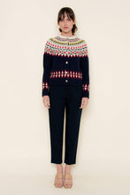 Load image into Gallery viewer, A woman wearing a navy blue Fair Isle cardigan sweater with red, green, yellow, and white patterned detailing across the chest, sleeves, and hem, styled against a neutral background.