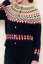 Load image into Gallery viewer, Close-up image of a navy Fair Isle cardigan sweater with red, green, and white knit patterns and crystal-style buttons, shown worn by a model from the shoulders to the waist.