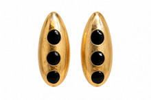 Load image into Gallery viewer, Gold-tone sculptural statement earrings with three glossy black circular accents displayed on a jewelry stand.
