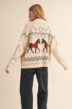 Load image into Gallery viewer, Person wearing a cream-colored sweater with horse designs on a beige background