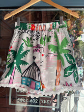 Load image into Gallery viewer, Colorful fabric with floral and abstract patterns displayed in a store window.