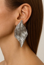 Load image into Gallery viewer, Silver leaf-shaped earring worn by a person with brown hair.