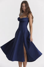 Load image into Gallery viewer, A model showcases a navy blue corset midi dress with a plait front, sleeveless design, and two shoulder straps, crafted from light, breathable fabric for a comfortable yet elegant look.