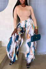 Load image into Gallery viewer, Model wearing abstract marble print draped wide-leg pants in blue, ivory, blush, and sand tones with layered flowing panels, styled with gold bangles and a teal handbag.