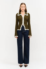 Load image into Gallery viewer, Model wearing olive green fitted double-zip knit top with ivory fuzzy trim, long sleeves, and pointed collar, styled with dark-wash wide-leg jeans.