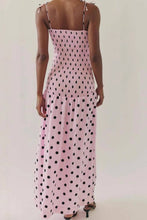 Load image into Gallery viewer, Pink polka dot midi dress with a smocked bodice, thin straps, and a flowy skirt, worn by a model.