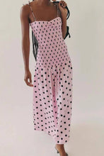 Load image into Gallery viewer, Pink polka dot midi dress with a smocked bodice, thin straps, and a flowy skirt, worn by a model.