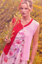 Load image into Gallery viewer, Woman in a floral dress and red cardigan sweater vest holding flowers in a field