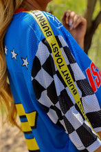 Load image into Gallery viewer, Woman wearing the All American Racing Team oversized mesh jersey featuring blue racing graphics, checkered sleeves, flame details, varsity lettering, and a large number 76 on the back.