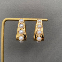 Load image into Gallery viewer, 18K gold-plated sculptural huggie earrings with four graduated white imitation pearl accents on each earring.