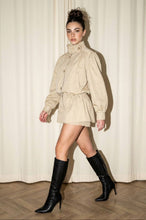 Load image into Gallery viewer, Model wearing the Kensington khaki utility skort set with funnel-neck button top, peplum waist and black knee-high boots.
