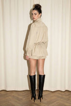 Load image into Gallery viewer, Model wearing the Kensington khaki utility skort set with funnel-neck button top, peplum waist and black knee-high boots.