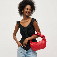 Load image into Gallery viewer, Red woven vegan leather clutch bag featuring a sculptural knotted top handle, curved silhouette, and gold-tone zipper closure, photographed on a model.