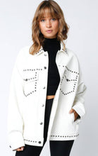 Load image into Gallery viewer, White vegan leather jacket with silver stud detailing, button-front closure, and front pockets, styled over a black top for a modern, edgy look.