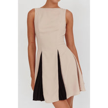 Load image into Gallery viewer, A sleeveless beige mini dress featuring a boat neckline and contrast black accents peeking through the pleats, creating a chic and versatile look suitable for any occasion.