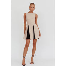 Load image into Gallery viewer, A sleeveless beige mini dress featuring a boat neckline and contrast black accents peeking through the pleats, creating a chic and versatile look suitable for any occasion.