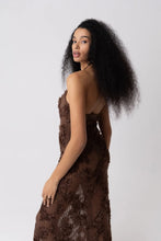 Load image into Gallery viewer, Model wearing a brown floral crochet halter maxi dress with open back and semi-sheer cotton fabric, styled for summer vacation, beach getaway, or resort wear look.