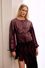 Load image into Gallery viewer, Model wearing burgundy asymmetric ruffle mini skirt with dramatic cascading layers and an elongated side panel, styled with a matching burgundy jacket