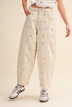 Load image into Gallery viewer, Model wearing cream barrel-leg jeans embellished with silver stud details throughout, featuring a high-rise waist and relaxed statement silhouette.