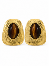 Load image into Gallery viewer, Oversized textured gold-tone statement earrings with irregular rounded-square frames and large glossy brown oval cabochon centers.