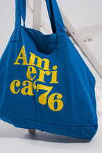 Load image into Gallery viewer, This America 76 Canvas Tote is a durable cotton canvas tote that has been made with a plain design and yellow text over the front. It has two urban twin handles, which help to give this bag a unique style. This bag is perfect for walking the dog, heading out to the beach with friends or going on a trip because of its durable design and open top concept. Made from durable 100% cotton canvas, and featuring an open top concept for convenient access, this roomy bag is ideal for everyday use.