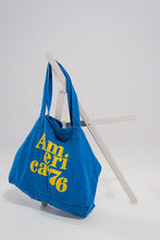 Load image into Gallery viewer, This America 76 Canvas Tote is a durable cotton canvas tote that has been made with a plain design and yellow text over the front. It has two urban twin handles, which help to give this bag a unique style. This bag is perfect for walking the dog, heading out to the beach with friends or going on a trip because of its durable design and open top concept. Made from durable 100% cotton canvas, and featuring an open top concept for convenient access, this roomy bag is ideal for everyday use.