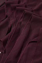 Load image into Gallery viewer, Burgundy asymmetric twill mini skirt featuring cascading sculptural ruffles and a dramatic elongated side hem on a white background.
