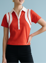 Load image into Gallery viewer, Red short-sleeve polo top with white contrast collar and panel detailing, styled with black shorts for a sporty chic look.
