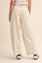 Load image into Gallery viewer, Model wearing cream barrel-leg jeans embellished with silver stud details throughout, featuring a high-rise waist and relaxed statement silhouette.
