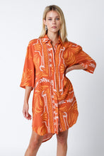Load image into Gallery viewer, Light and breezy, this versatile shirt dress features a gorgeous orange and cream print, 3/4 sleeves and a button closure at the front. Perfect for running errands or vacation days at the beach. This versatile and chic shirt dress can be worn as a dress, a swimsuit cover up or a top. The styling possibilities are endless. 
