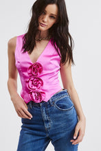 Load image into Gallery viewer, Introducing our Pink Rosette Satin Vest Top - Our take on a Y2K-inspired vest. Crafted from a solid satin fabric with exquisite rosette bud detailing on the front, it adds a trendy twist to a classic style. The V neckline, pointed front hem, and cropped fit embrace the perfect blend of contemporary and timeless charm. Pair this charming vest with denim or trousers to complete the look! Model is wearing a size Small. Dress it up or  down!
