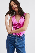 Load image into Gallery viewer, Introducing our Pink Rosette Satin Vest Top - Our take on a Y2K-inspired vest. Crafted from a solid satin fabric with exquisite rosette bud detailing on the front, it adds a trendy twist to a classic style. The V neckline, pointed front hem, and cropped fit embrace the perfect blend of contemporary and timeless charm. Pair this charming vest with denim or trousers to complete the look! Model is wearing a size Small. Dress it up or  down!
