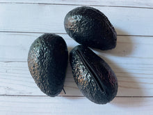 Load image into Gallery viewer, Realistic avocado-shaped coin purse with zipper, keychain ring, and bag charm attachment displayed on a wood background.
