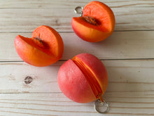 Load image into Gallery viewer, Realistic peach-shaped coin purse with zipper, keychain ring, and bag charm attachment displayed on a wood background.
