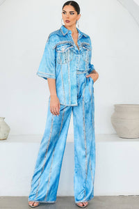 Woman wearing a light blue denim looking satin outfit against a white background